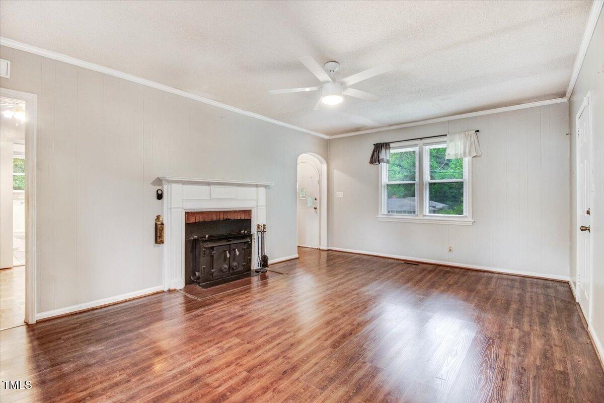607 East Geer Street Durham, NC 27701 - Photo 9 of 23 an empty room with wooden floor fireplace and windows