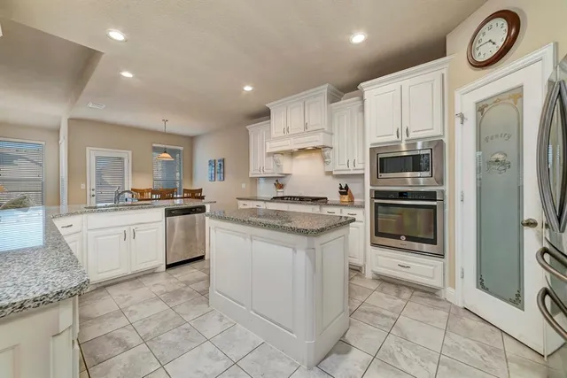 a kitchen with granite countertop a refrigerator and a stove top oven