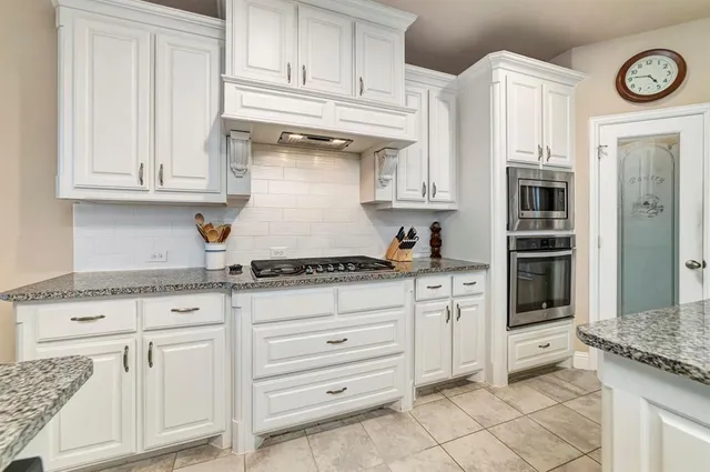 a kitchen with granite countertop white cabinets and stainless steel appliances