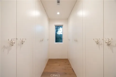 a view of a hallway with wooden floor and a bathroom