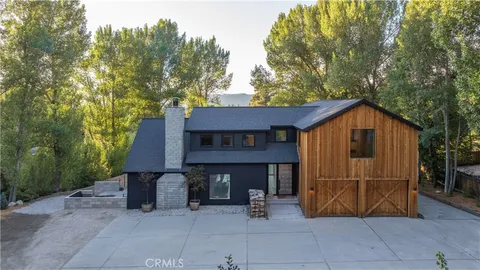 a view of a house with large trees and wooden fence