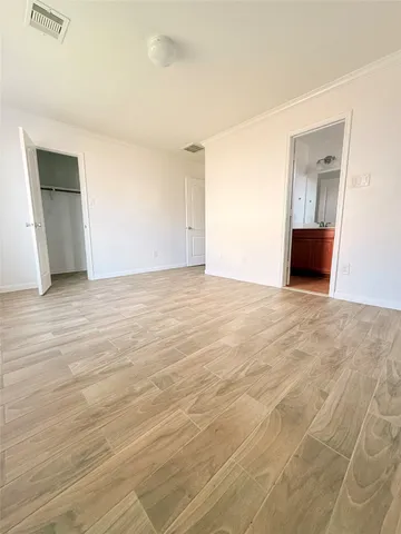 a view of an empty room with wooden floor and cabinet