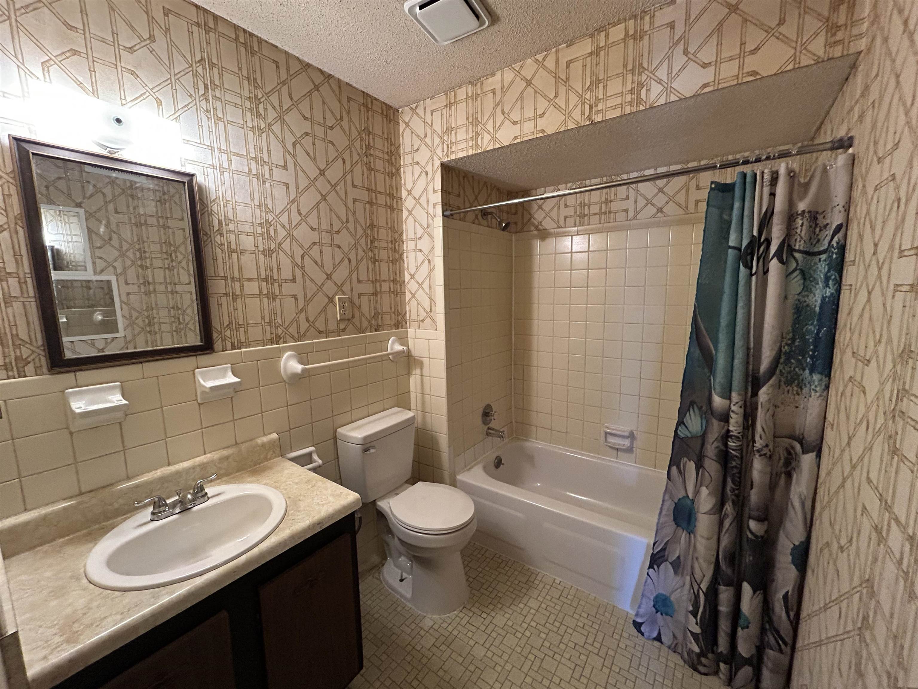 2800 Clarke Road, Unit 2 Memphis, TN 38115 - Photo 14 of 18 Bathroom featuring a vanity with a laminate countertop, an oval sink, a toilet, a tiled tub-shower combination, and patterned wallpaper