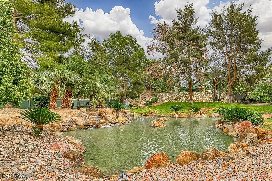 9 Quail Run Road Henderson, NV 89014 - Photo 55 of 57 A tranquil pond with cascading rocks flows into a lush, manicured garden oasis.