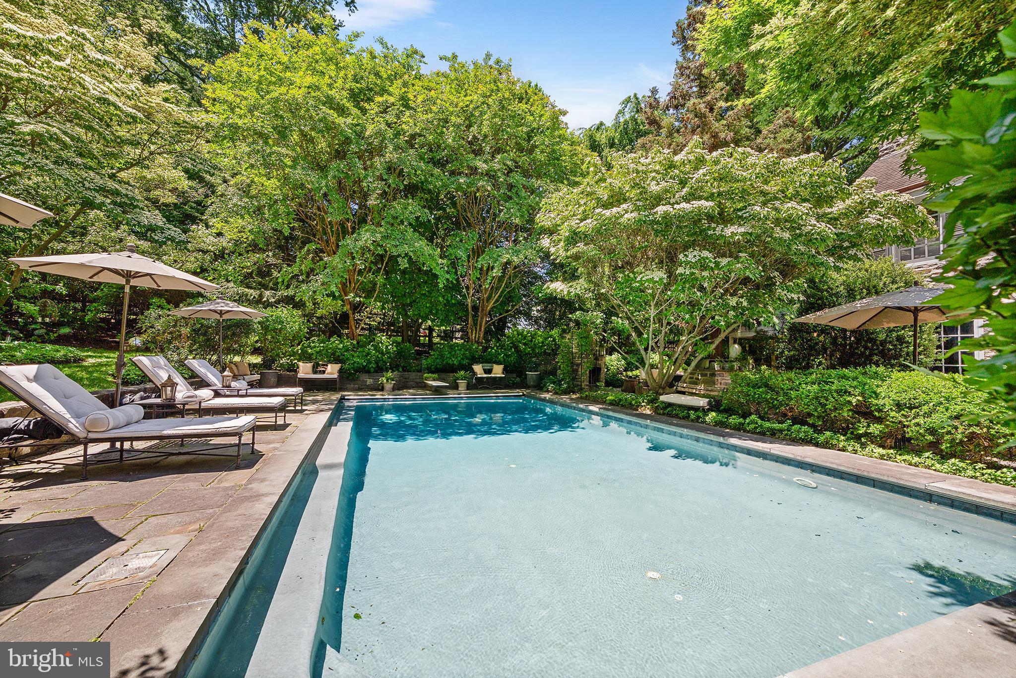 311 Millbank Road Bryn Mawr, PA 19010 - Photo 46 of 54 a view of a swimming pool with lawn chairs under an umbrella