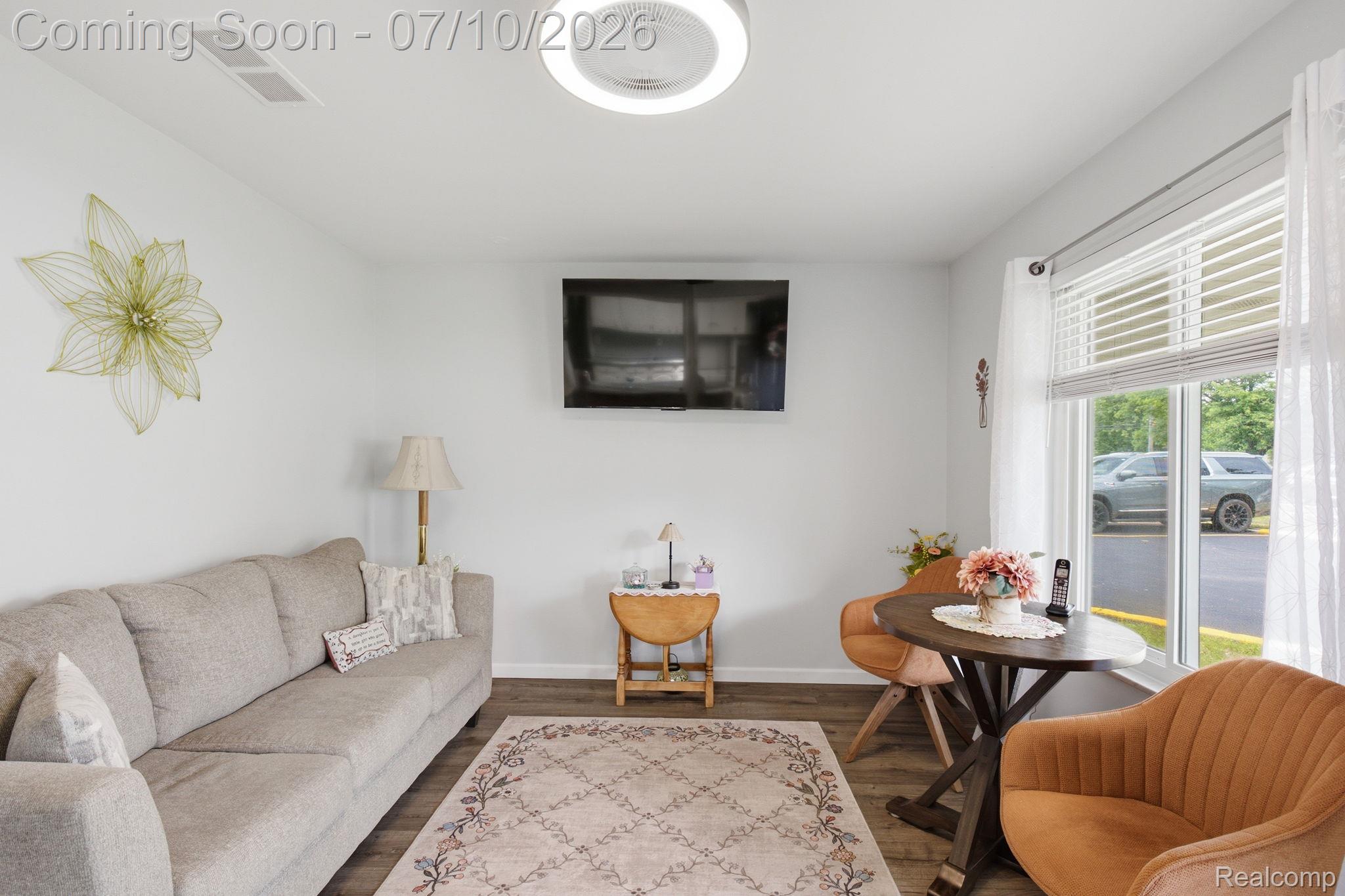 1501 River Road, Unit 301 St. Clair, MI 48079 - Photo 4 of 32 Living area featuring wood-finish flooring, white walls, and a large window with blinds and sheer curtains