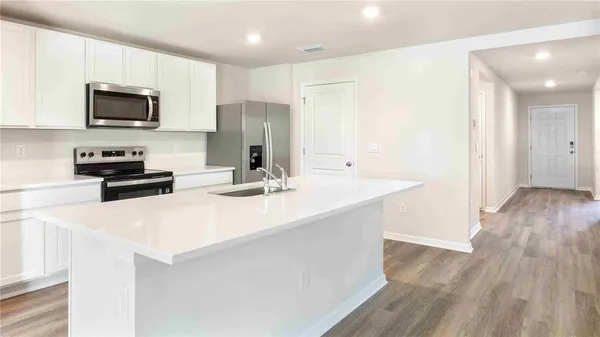 a kitchen with stainless steel appliances a microwave a stove a sink and white cabinets