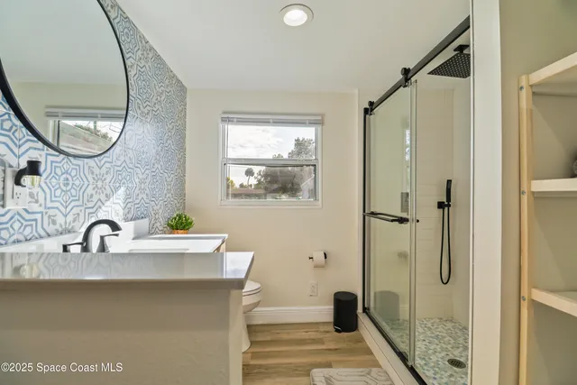 a bathroom with a sink a mirror a vanity and a shower