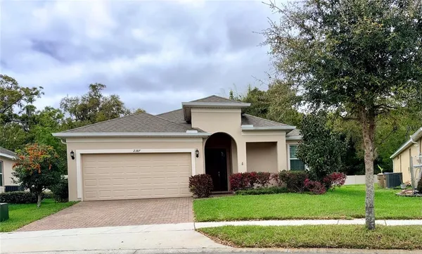a front view of a house with a garden and trees