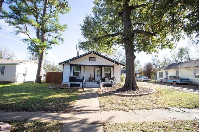 a large tree in front of a house with a yard