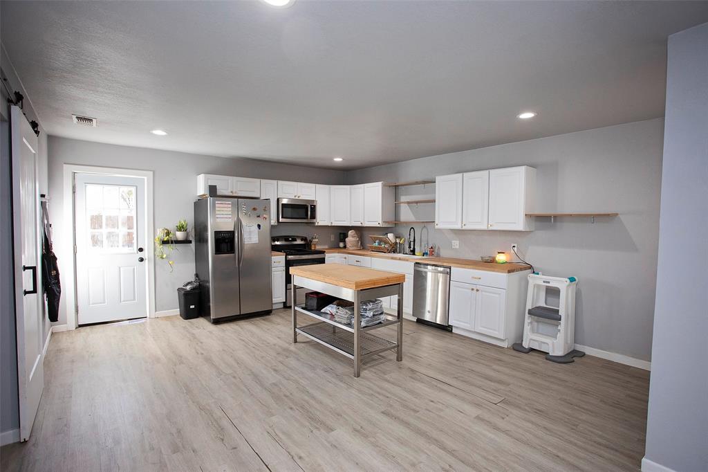 723 Plum Street Graham, TX 76450 - Photo 5 of 20 a kitchen with a wooden floor and a refrigerator