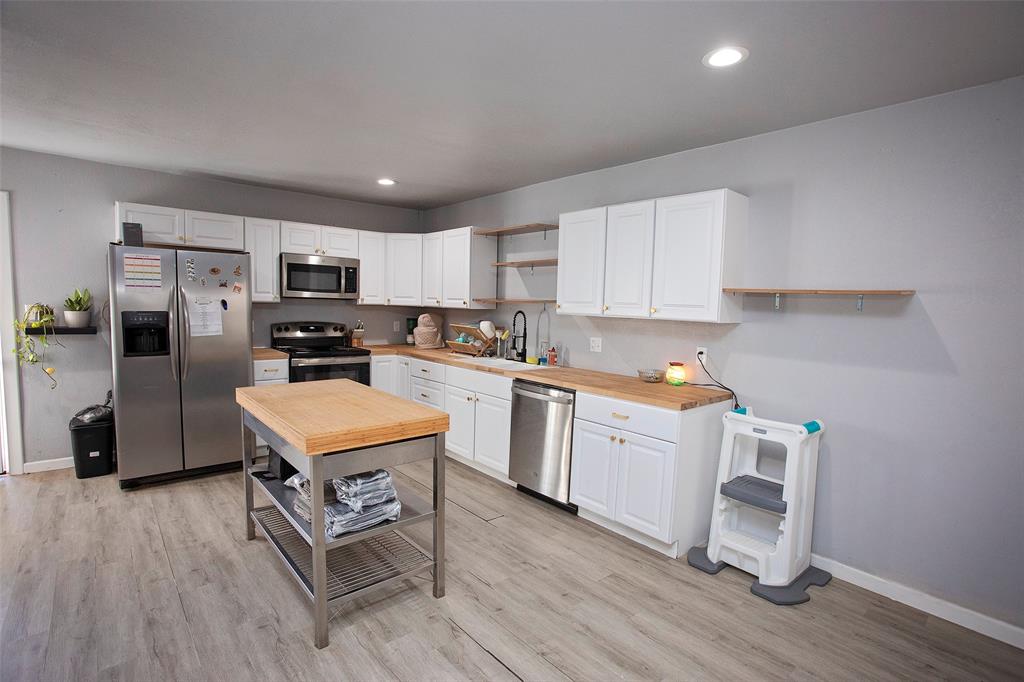 723 Plum Street Graham, TX 76450 - Photo 6 of 20 a kitchen with a sink a microwave a refrigerator and cabinets