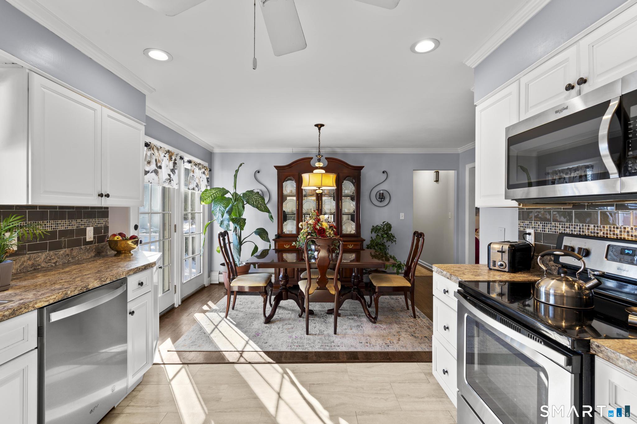710 East Main Street Stratford, CT 06614 - Photo 4 of 34 a kitchen with stainless steel appliances granite countertop a stove top oven a sink dishwasher a dining table and chairs with wooden floor