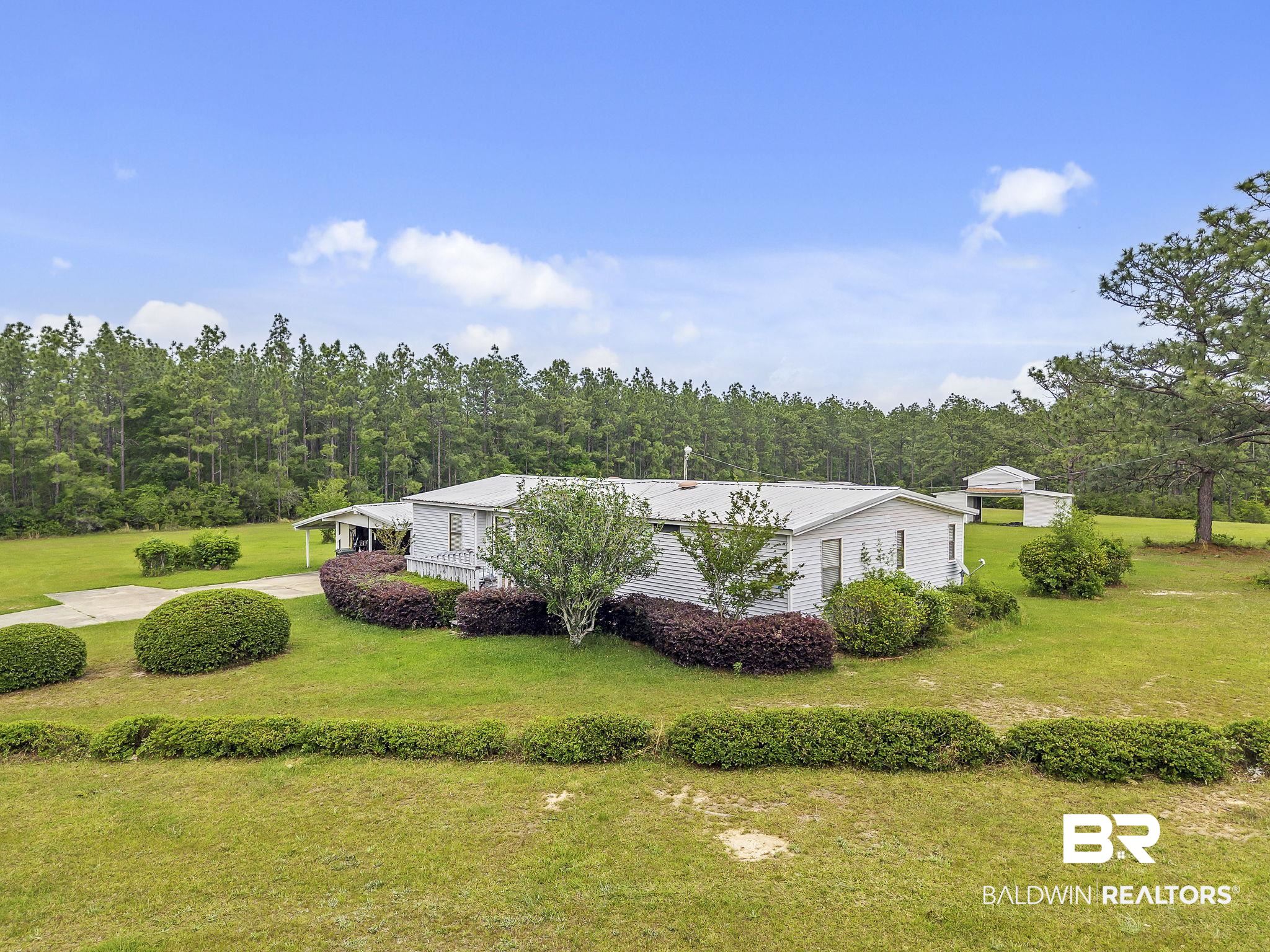 29792 County Road 65 Loxley, AL 36551 - Photo 2 of 39 View of side of property featuring a lawn, a wooded view, and metal roof