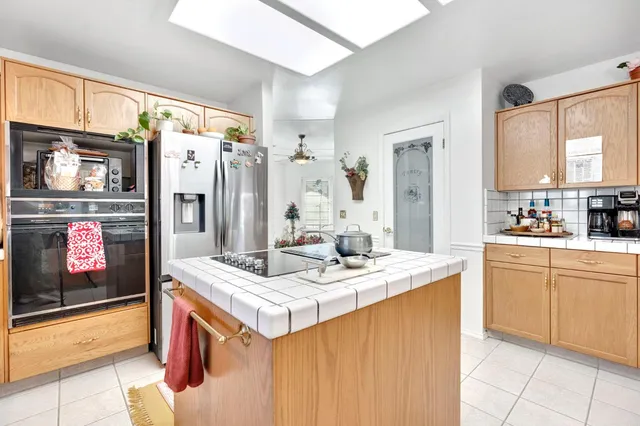 a kitchen with stainless steel appliances kitchen island granite countertop a refrigerator and a stove top oven