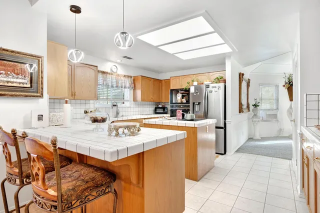 a kitchen with stainless steel appliances granite countertop a sink a stove a refrigerator and island