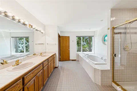 a bathroom with a tub a sink and a large mirror