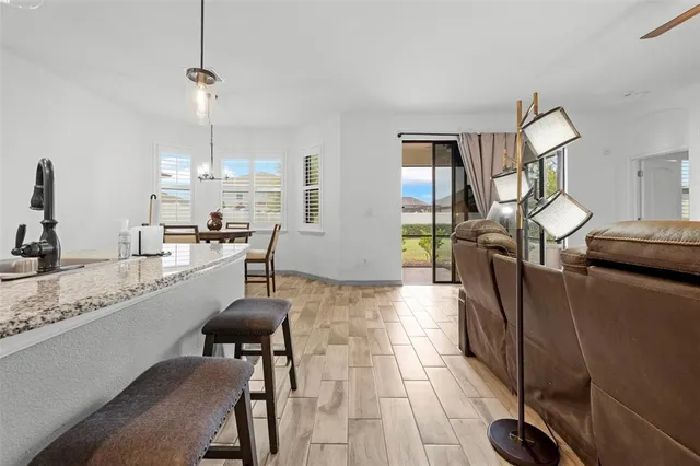 a living room with furniture a chandelier and kitchen view