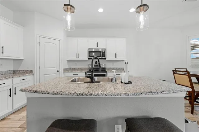 a kitchen with kitchen island granite countertop a sink a stove a counter space and cabinets