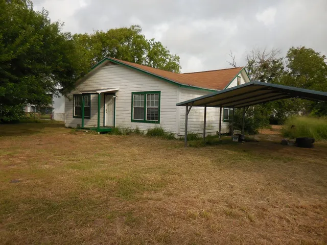a view of a house with backyard and trees