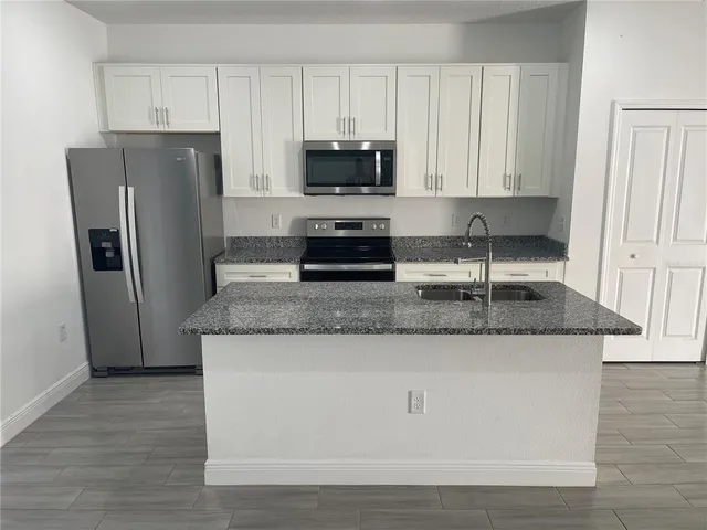 a kitchen with granite countertop a refrigerator and a sink