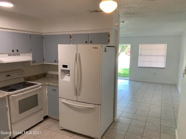 a white refrigerator freezer and a stove sitting inside of a kitchen