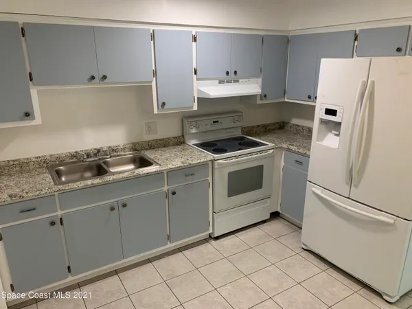 a kitchen with granite countertop white cabinets and white appliances
