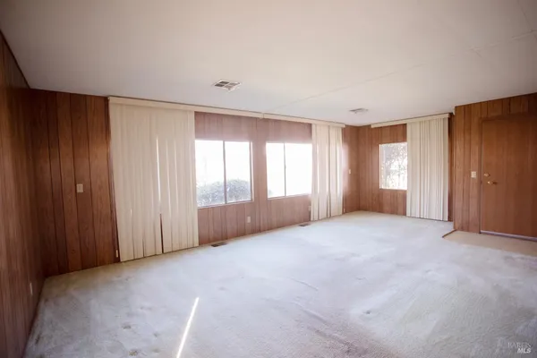 a view of an empty room with window and closet area