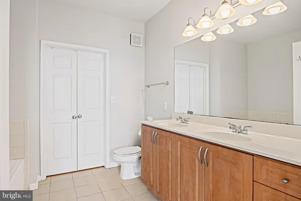 a spacious bathroom with a granite countertop sink a toilet and a mirror