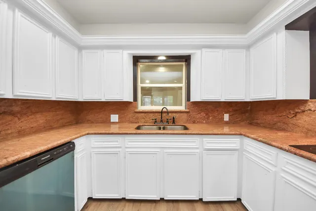 a kitchen with granite countertop white cabinets and a sink