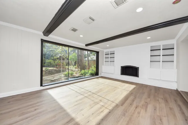 a view of empty room with wooden floor and fireplace
