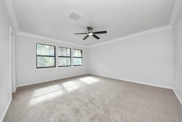 an empty room with windows and ceiling fan