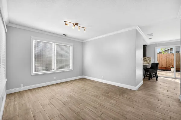 a view of an empty room with a window and wooden floor