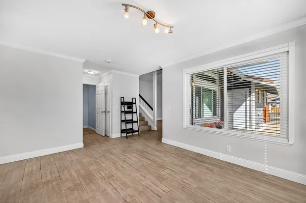 a view of an empty room with a window and wooden floor