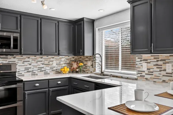 a kitchen with granite countertop a sink a stove and cabinets