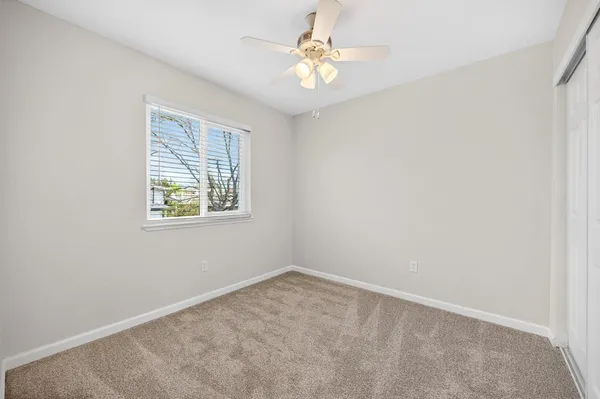 an empty room with a window and a fan