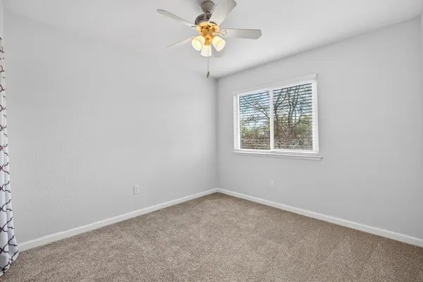 an empty room with a window and a fan