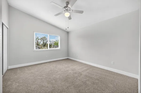an empty room with a window and a fan