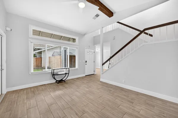 a view of an empty room with wooden floor and a window