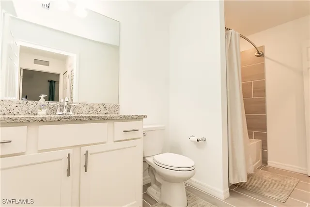 a bathroom with a granite countertop sink mirror vanity and toilet