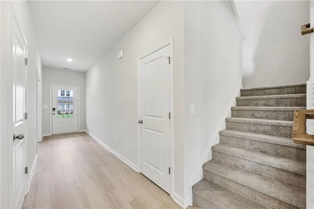 a view of an empty room with wooden floor a fireplace and windows