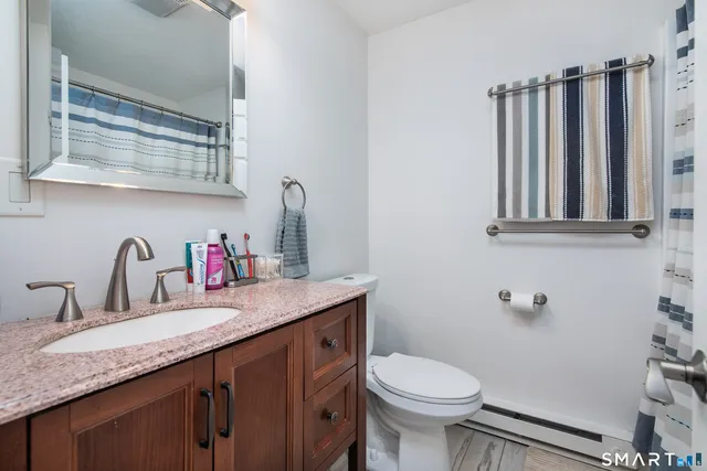 a bathroom with a granite countertop toilet sink and mirror