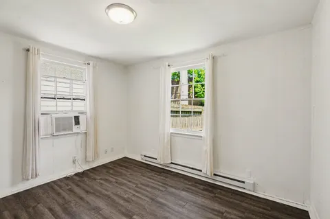 an empty room with wooden floor cabinet and windows