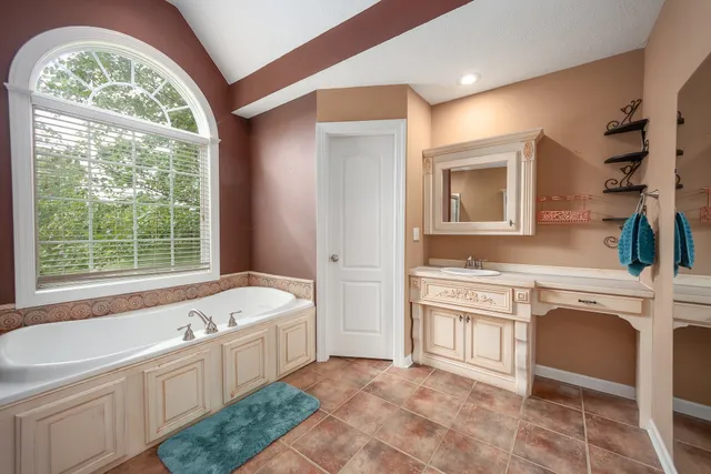 a spacious bathroom with a tub sink and mirror