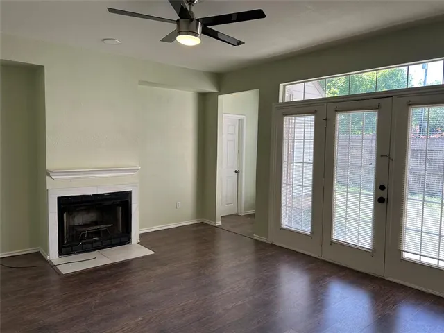 a view of an empty room with wooden floor fireplace and a window