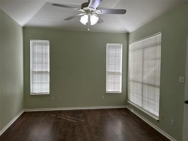 an empty room with wooden floor closet and windows
