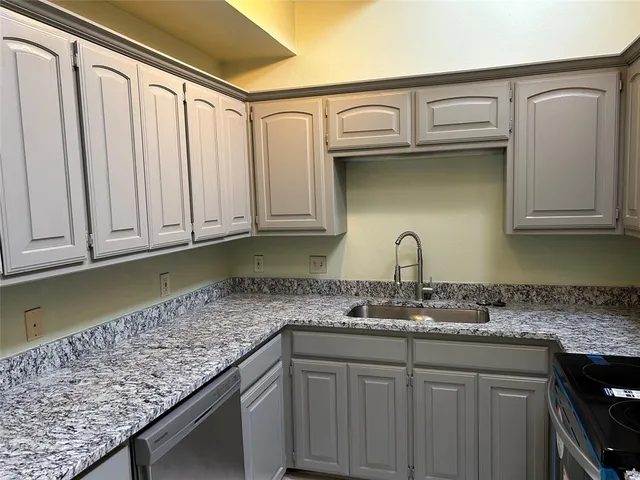 a kitchen with granite countertop a sink and cabinets