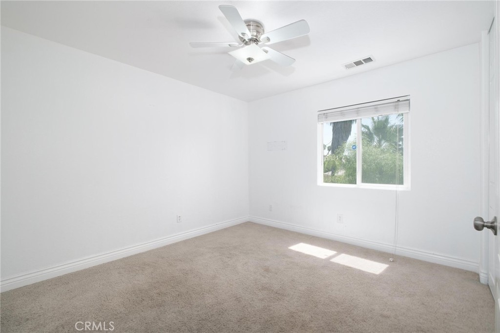 7940 Shadow Trails Lane Jurupa Valley, CA 92509 - Photo 16 of 34 an empty room with windows and ceiling fan