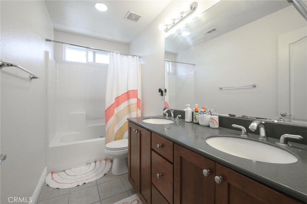 7940 Shadow Trails Lane Jurupa Valley, CA 92509 - Photo 31 of 34 a bathroom with a granite countertop double vanity sink a mirror and a toilet