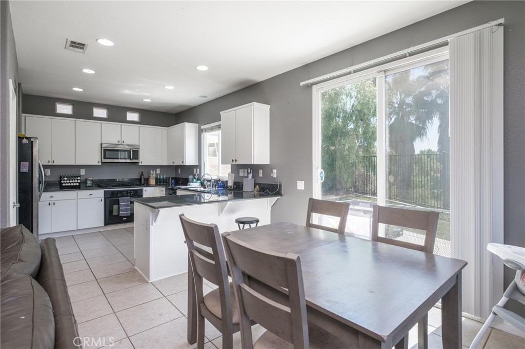7940 Shadow Trails Lane Jurupa Valley, CA 92509 - Photo 7 of 34 a kitchen with stainless steel appliances granite countertop a stove a refrigerator a sink and white cabinets with wooden floor